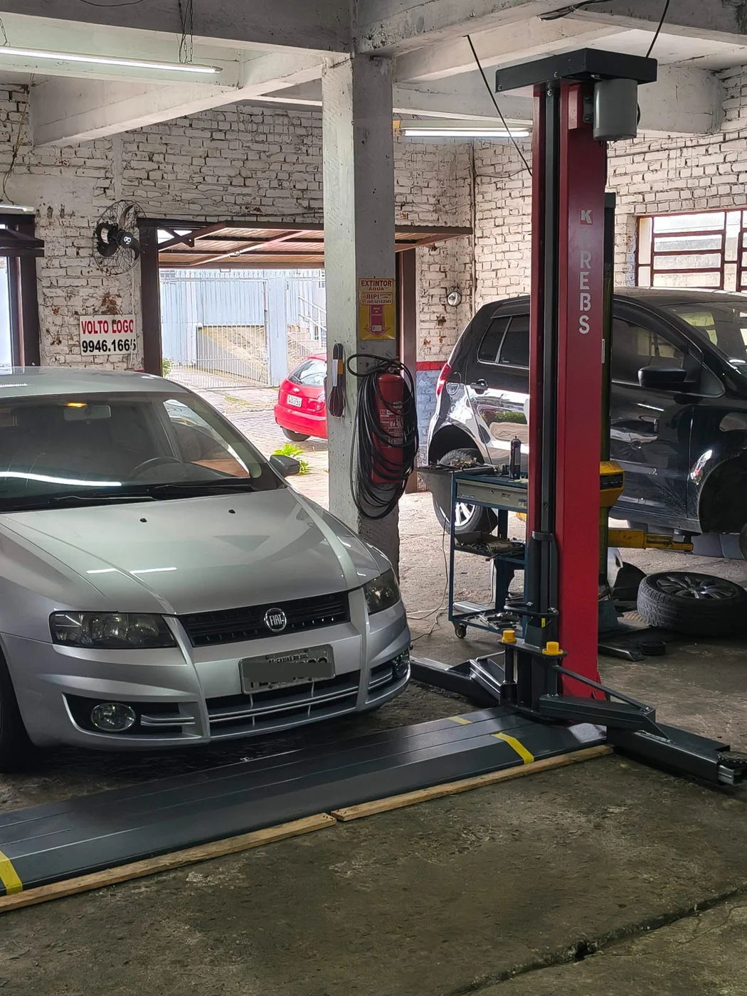 Automóveis e elevador no interior da Oficina Roberto